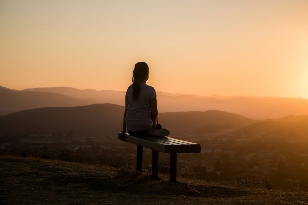 Woman sitting peacefully overlooking a calm mountain view